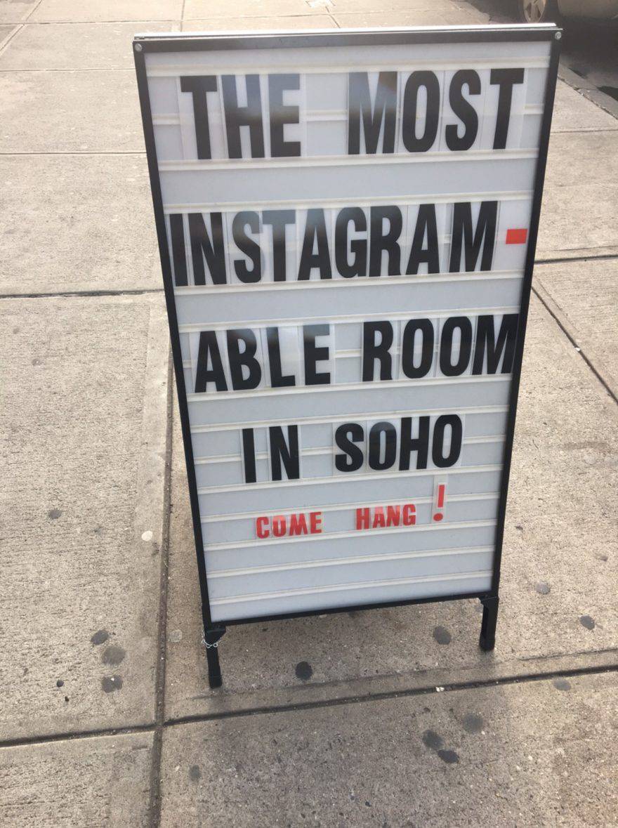 A sign outside Glossier’s Soho NYC HQ says: The most instagram-able room in Soho. Come hang!